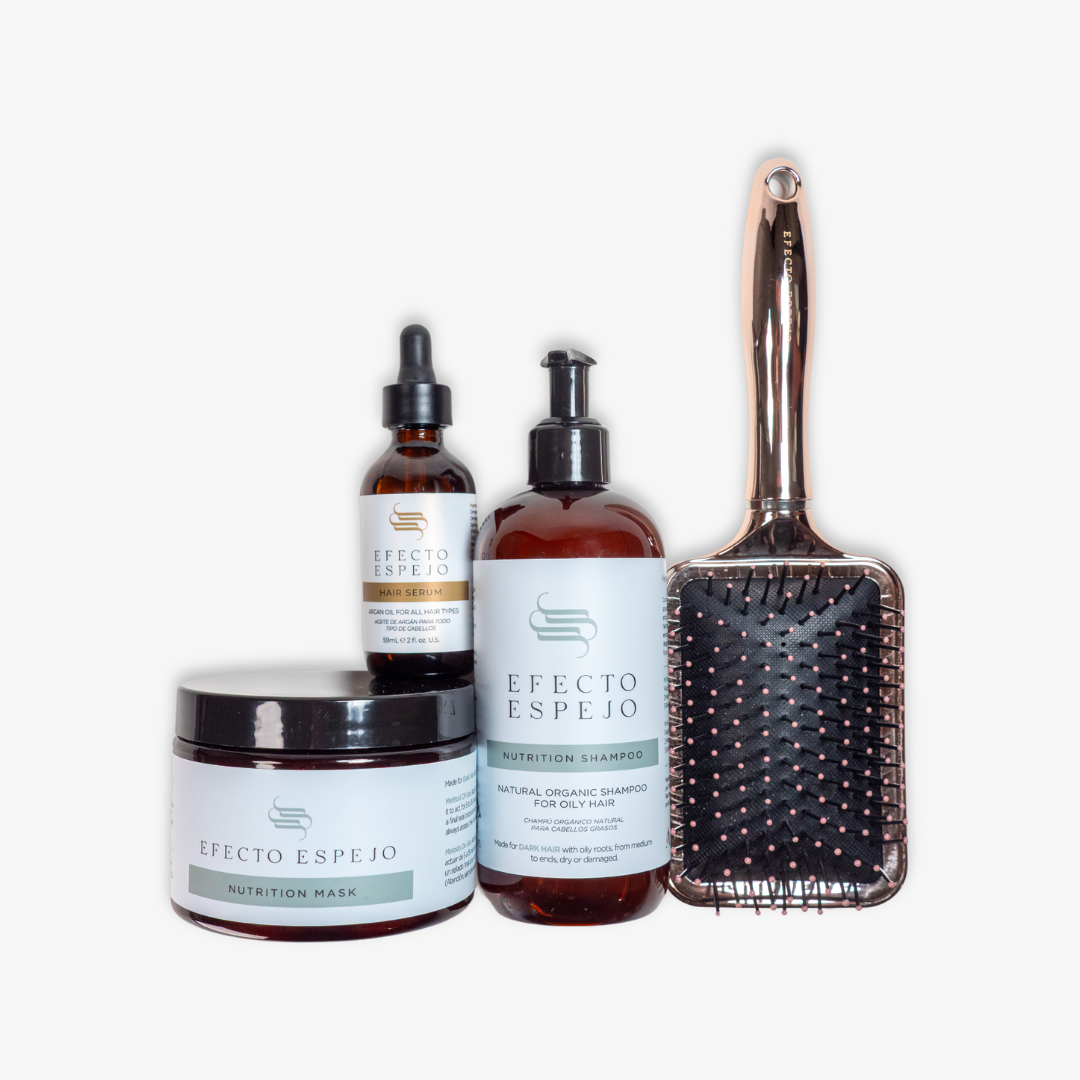 The Efecto Espejo Shine Kit arranged with the shampoo, mask, serum, and brush on a sleek, modern vanity.