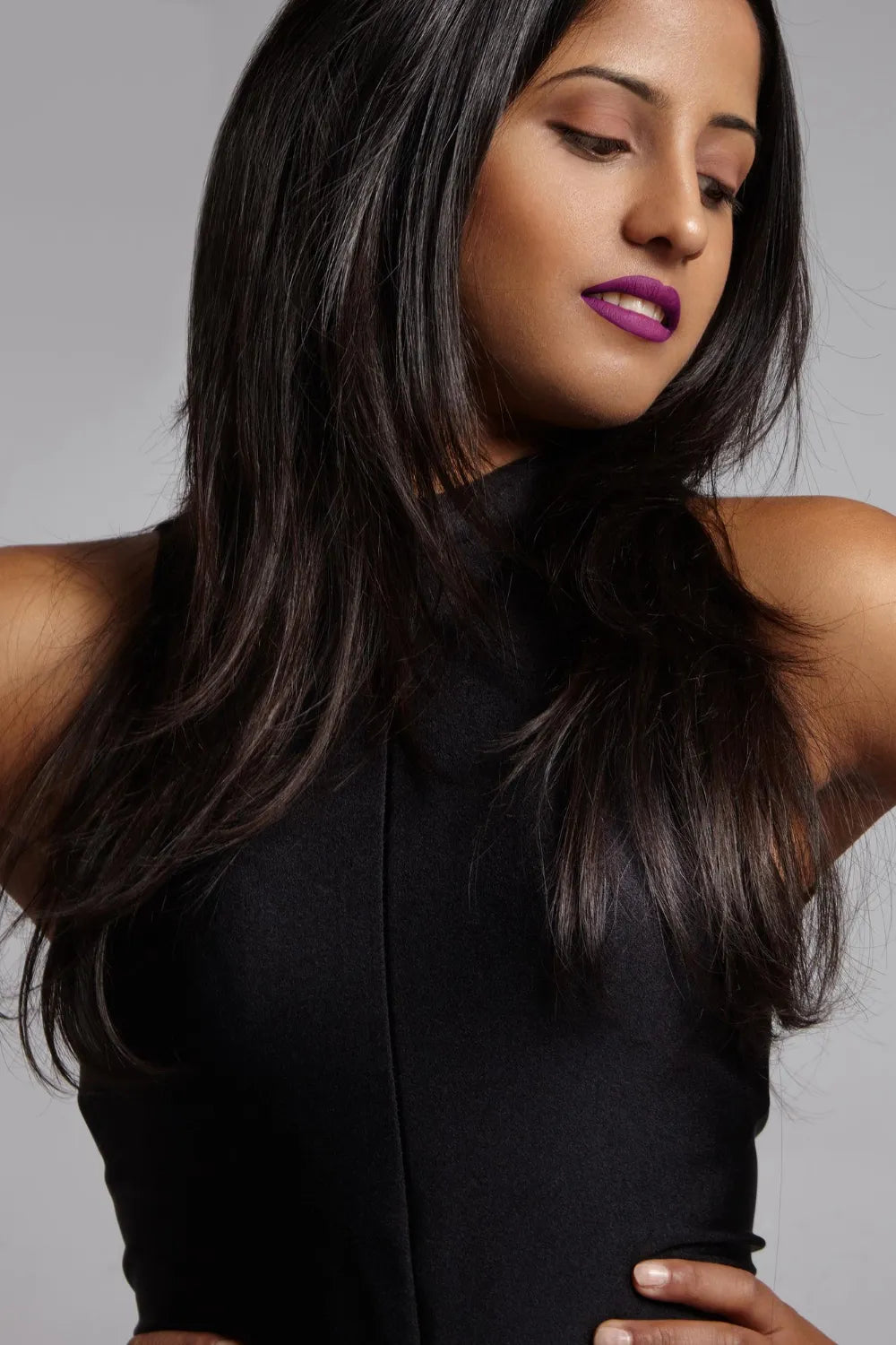 Woman with healthy hair watching aside wears bright matte lipstick